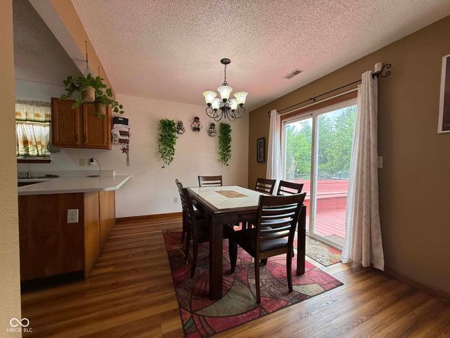 dining area featuring a textured ceiling, a chandelier, and dark wood-style flooring | Image 25
