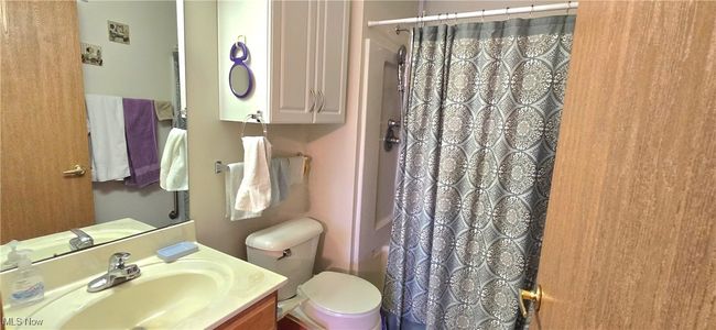 Full bathroom with toilet, vanity, and curtained shower | Image 23