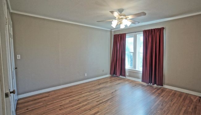 Spare room featuring wood finished floors, a ceiling fan, and ornamental molding | Image 7