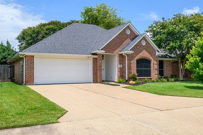 Traditional-style home featuring an attached garage, driveway, brick siding, and roof with shingles | Image 23
