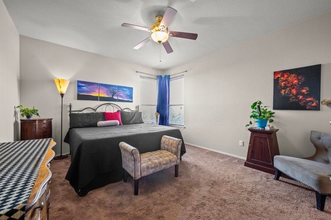 The primary bedroom is roomy with a high ceiling, a ceiling fan, and cozy carpet flooring throughout. | Image 12