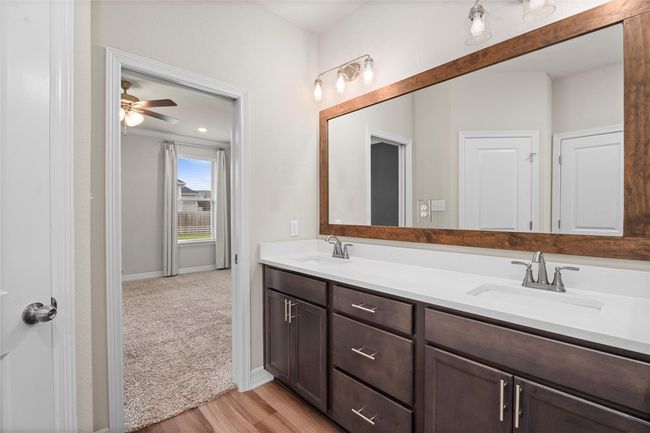 Full bathroom featuring double vanity, wood finished floors, baseboards, and ceiling fan | Image 19