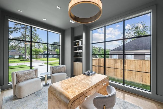 This moody office features oversized windows that allow soft, natural light to pour in, creating a balanced, inviting atmosphere. Custom bookshelves line the walls, offering both style and storage, while a "hidden" closet seamlessly blends into the design, adding an element of surprise and functionality. | Image 28