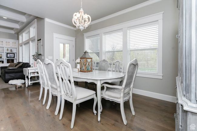 Dining area featuring wood finished floors, crown molding, baseboards, and a notable chandelier | Image 35
