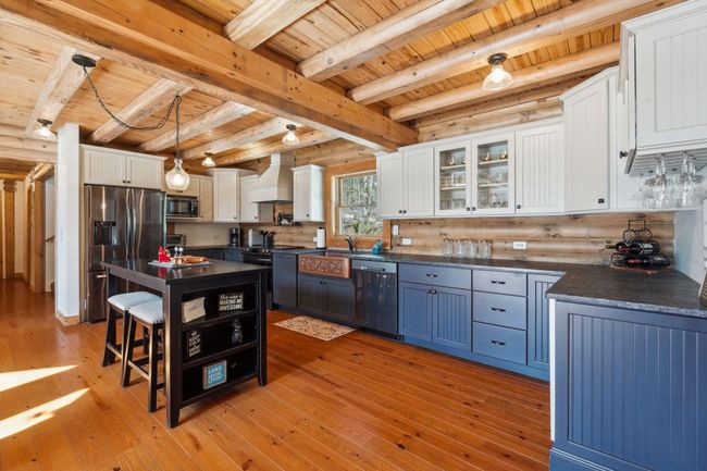 With leathered granite, copper sink, two-toned cabinets, black stainless steel appliances and hardwood floors | Image 7
