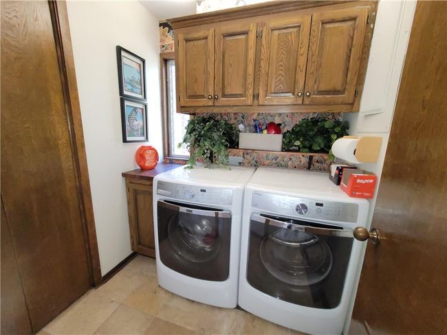 Washroom featuring independent washer and dryer, cabinet space, and baseboards | Image 51