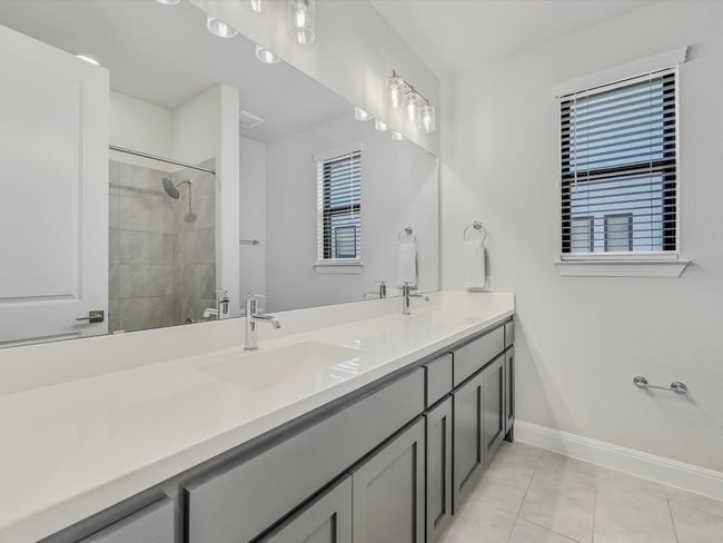 Bathroom with double vanity, tile patterned flooring, and tiled shower | Image 27