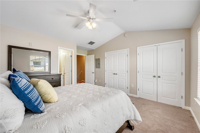 Bedroom featuring visible vents, baseboards, vaulted ceiling, light carpet, and two closets | Image 10
