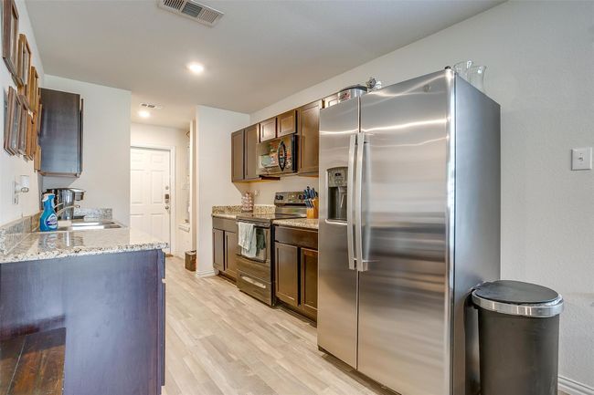 Kitchen with black and stainless appliances and vinyl flooring | Image 12