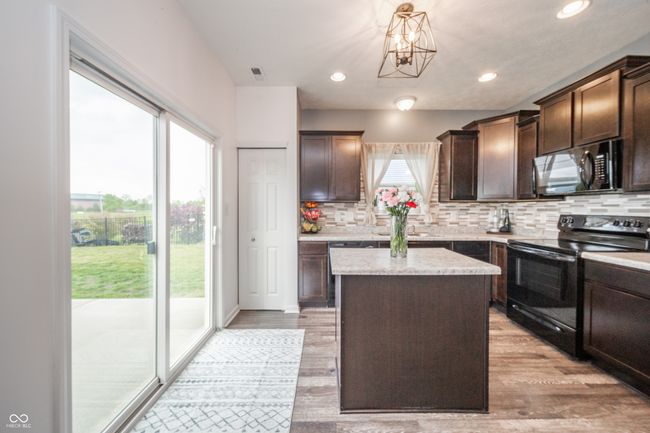 kitchen featuring black appliances, dark brown cabinetry, tasteful backsplash, a kitchen island, and recessed lighting | Image 17