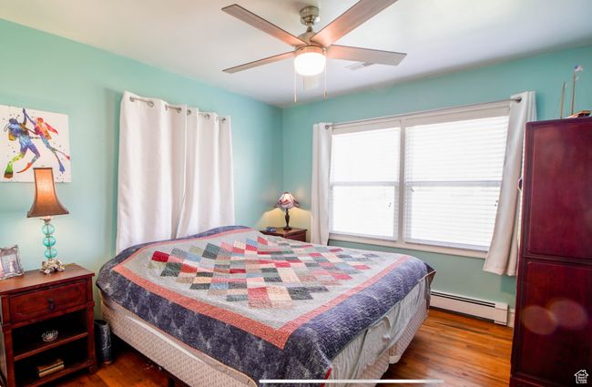 Bedroom with baseboard heating, wood finished floors, multiple windows, and a ceiling fan | Image 20