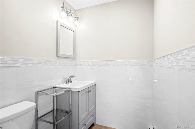 Half bath with tile walls, a wainscoted wall, toilet, and vanity | Image 18
