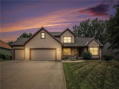 View of front of home with a garage, a porch, and a lawn | Image 1