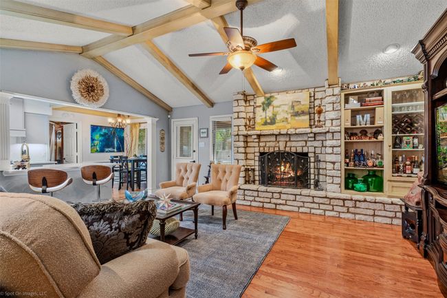 Large living area is conveniently connected with the kitchen and breakfast areas and features, hardwood flooring, a cathedral style ceiling, wood beam accents, a decorative stone fireplace | Image 7