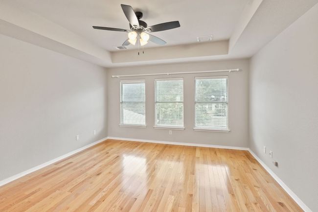Spare room featuring light wood finished floors, a ceiling fan, and a tray ceiling | Image 23