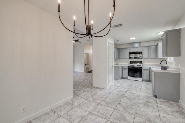 Kitchen featuring gray cabinetry, white gas stove, black microwave, a chandelier, and light countertops | Image 11