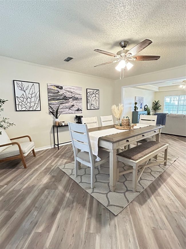 Dining area with ceiling fan, a textured ceiling, wood finished floors, and ornamental molding | Image 18