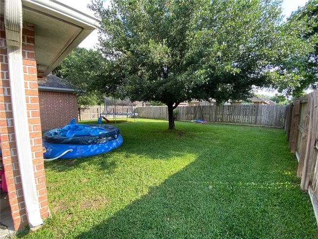 Fenced backyard featuring a trampoline | Image 11
