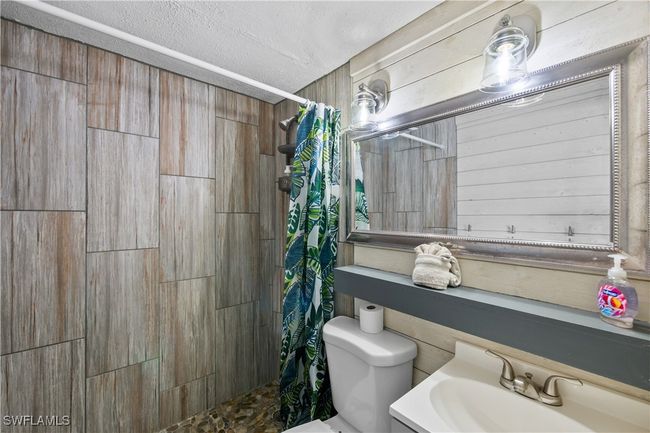 Bathroom with toilet, a textured ceiling, walk in shower, and vanity | Image 29