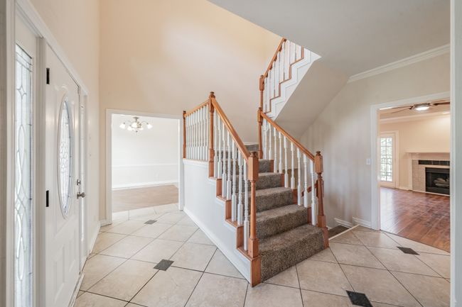 Foyer featuring ceiling fan with notable chandelier, light wood-type flooring, ornamental molding, and a tiled fireplace | Image 4