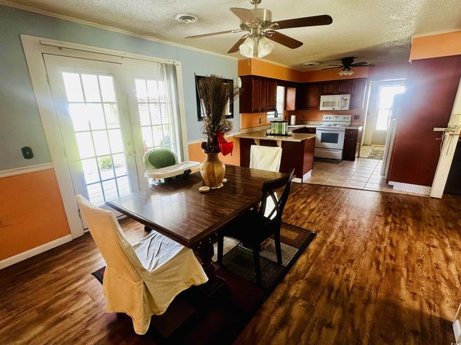 Dining room featuring crown molding, a textured ceiling, a ceiling fan, visible vents, and wood finished floors | Image 6