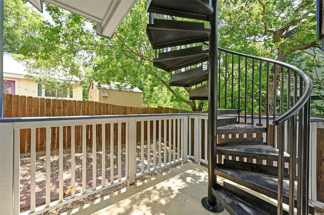 An iron circular staircase off of a backdoor covered patio leads to the private rooftop deck. | Image 22