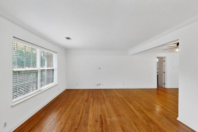 Empty room with ornamental molding, wood finished floors, and ceiling fan | Image 6