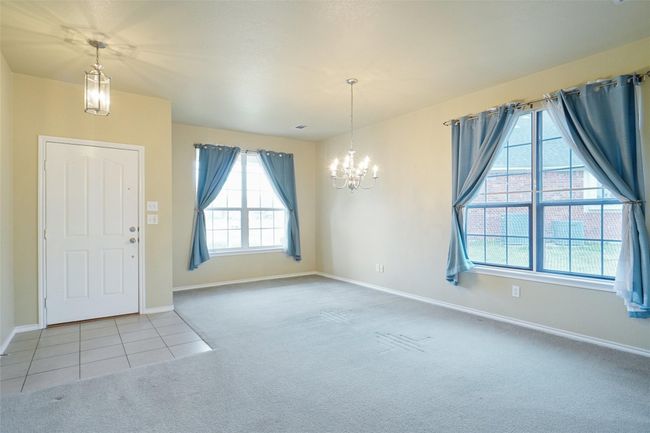 Carpeted foyer with baseboards, tile patterned flooring, and a notable chandelier | Image 4