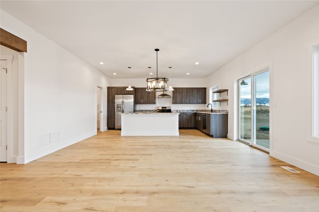 Kitchen featuring dark brown cabinetry, stainless steel appliances, wall chimney exhaust hood, recessed lighting, and hanging light fixtures | Image 8