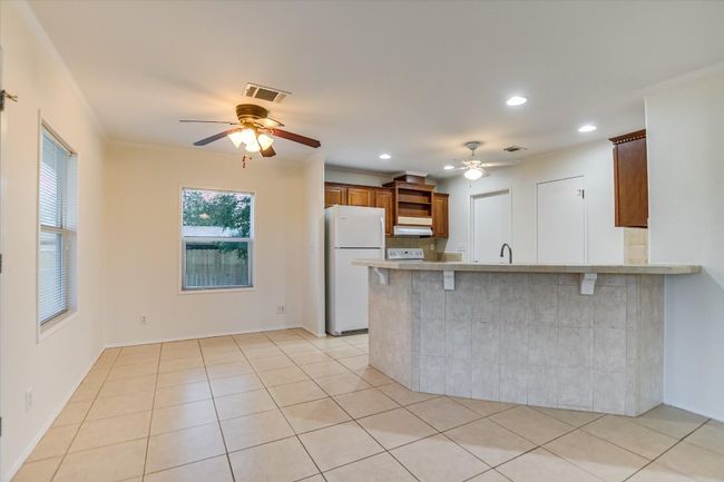 Kitchen with a peninsula, freestanding refrigerator, a breakfast bar area, ceiling fan, and light countertops | Image 11