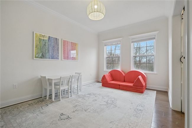 Light-filled flex room off of the family room, featuring double glass barn doors, crown molding, large windows and neutral finishes. Offers endless possibilities for use as a playroom, home office, craft space, or study area. Beautiful hardwood floors and crisp white walls provide a clean and inviting backdrop. | Image 19