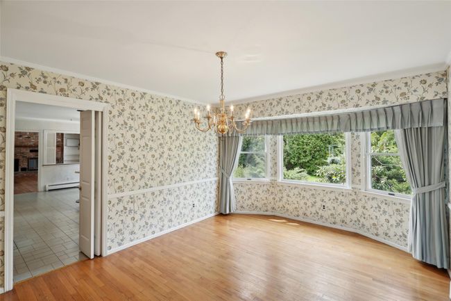 Unfurnished dining area featuring a chandelier, wallpapered walls, hardwood / wood-style floors, and baseboard heating | Image 18