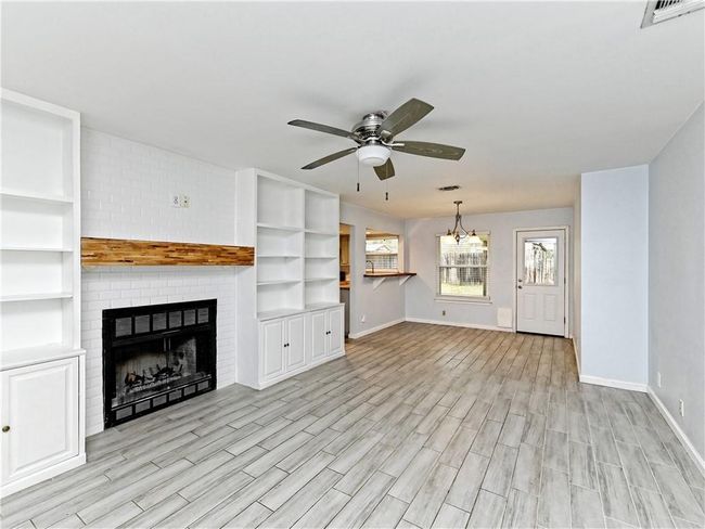 Unfurnished living room featuring a ceiling fan, light wood finished floors, a fireplace, and a chandelier | Image 25