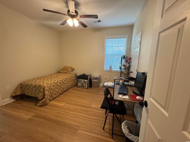 Bedroom with light wood finished floors, a desk, baseboards, and a ceiling fan | Image 16