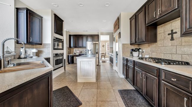 Kitchen with appliances with stainless steel finishes, light countertops, a sink, and light tile patterned flooring | Image 15