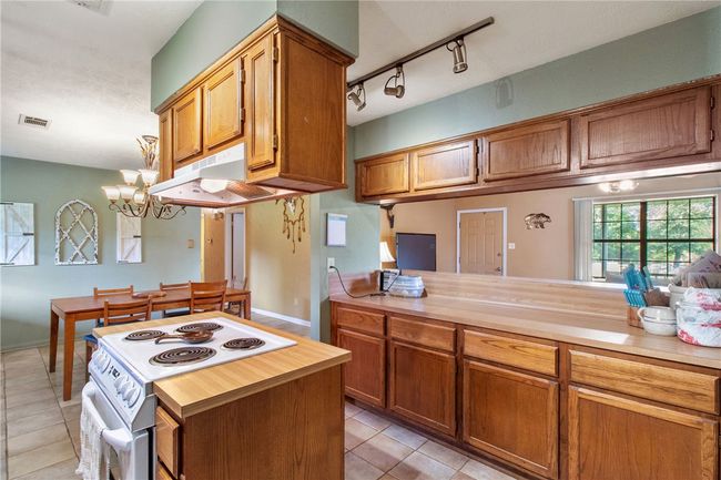Kitchen featuring white electric range, light tile patterned floors, light countertops, and brown cabinetry | Image 11