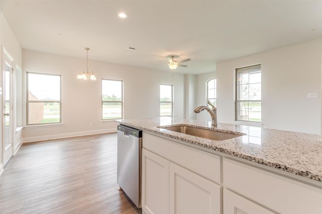 Kitchen with sink, dishwasher, white cabinetry, hanging light fixtures, and light stone counters | Image 15