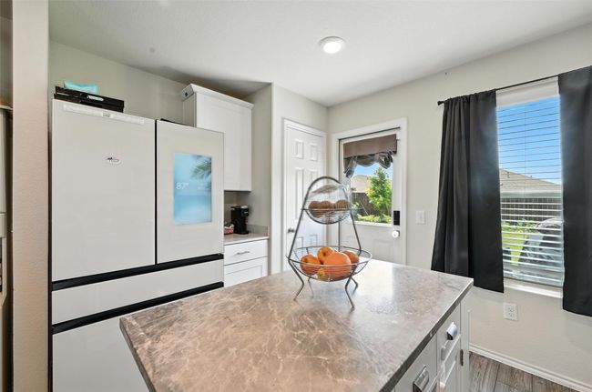 Kitchen with freestanding refrigerator, wood finished floors, white cabinets, and light countertops | Image 13