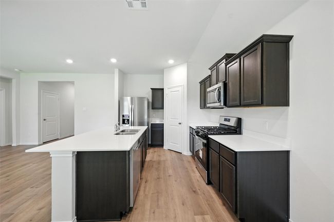 Kitchen featuring appliances with stainless steel finishes, light wood-style floors, a kitchen island with sink, light countertops, and recessed lighting | Image 9