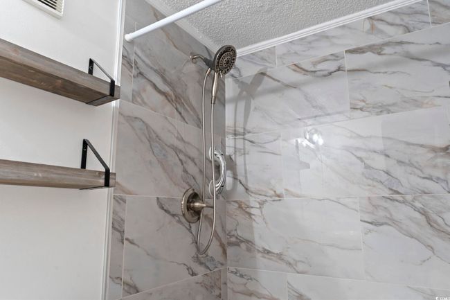 Room details featuring visible vents and a marble finish shower | Image 10