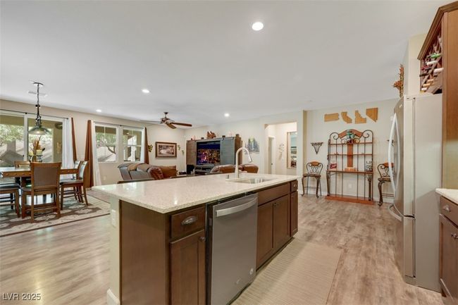 Kitchen featuring stainless steel appliances, a center island with sink, a sink, ceiling fan, and light wood-style flooring | Image 17