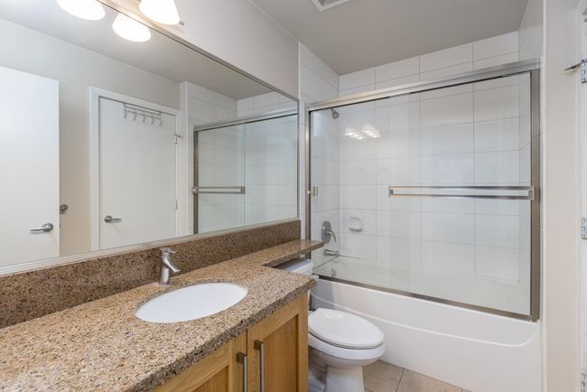 Full bath with vanity, tile patterned flooring, bath / shower combo with glass door, and toilet | Image 23