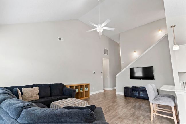 Living area with a ceiling fan, high vaulted ceiling, visible vents, and wood finished floors | Image 7