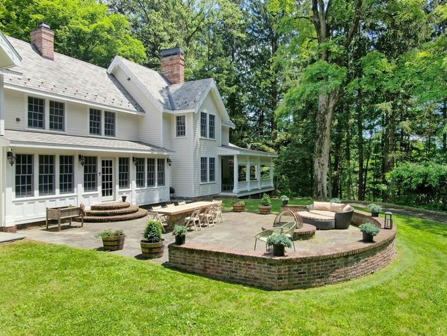 Back of house with a sunroom, a patio, a lawn, outdoor lounge area, and a high end roof | Image 42