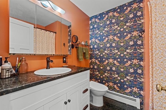 Full bathroom featuring a shower with shower curtain, vanity, a baseboard radiator, and toilet | Image 17