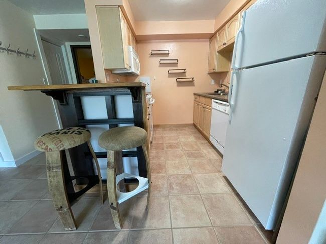 Kitchen featuring light tile patterned floors, white appliances, and a sink | Image 16