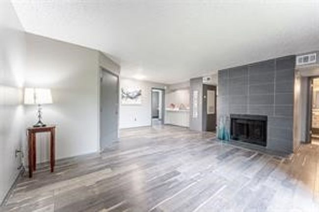 Unfurnished living room with wood finished floors and a fireplace | Image 4