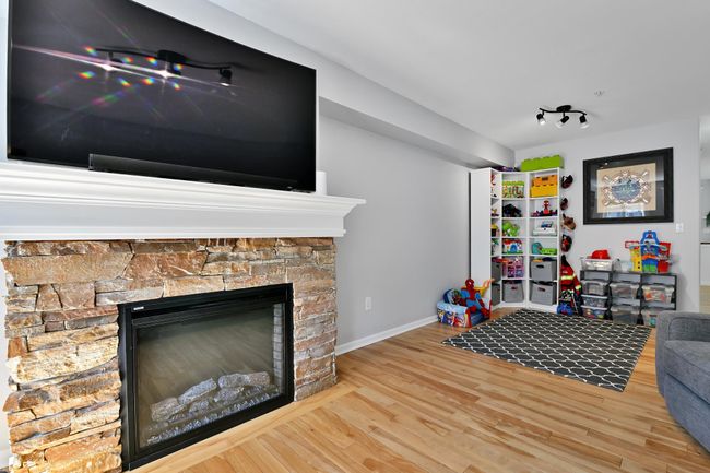 Rec room with wood finished floors, baseboards, and a stone fireplace | Image 4
