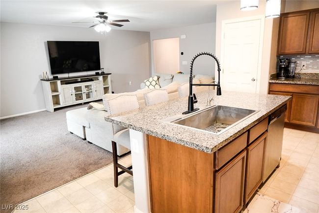 Kitchen with a ceiling fan, brown cabinets, open floor plan, and a sink | Image 11