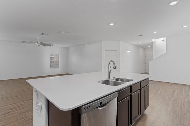 Kitchen featuring a center island with sink, dishwasher, open floor plan, light countertops, and a sink | Image 9